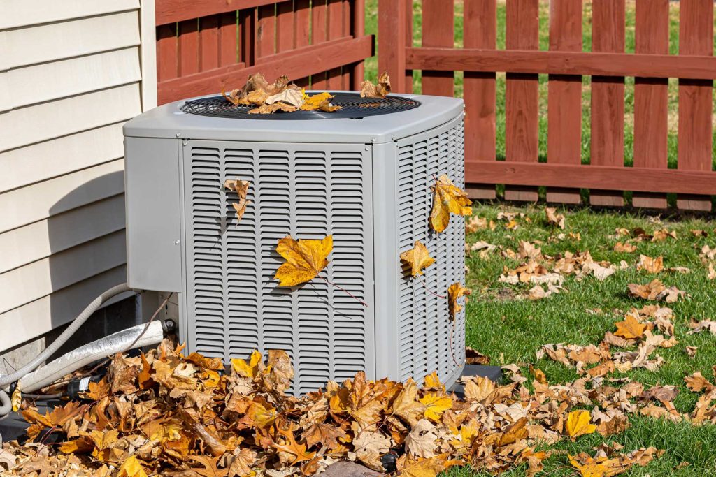 Dirty air conditioning unit covered in leaves