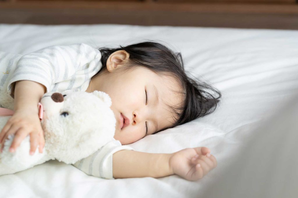 young child sleeping with a teddy bear