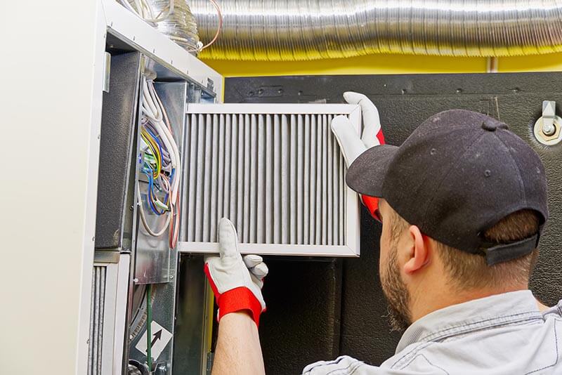 service technician changing dirty air filter in the central ventilation system