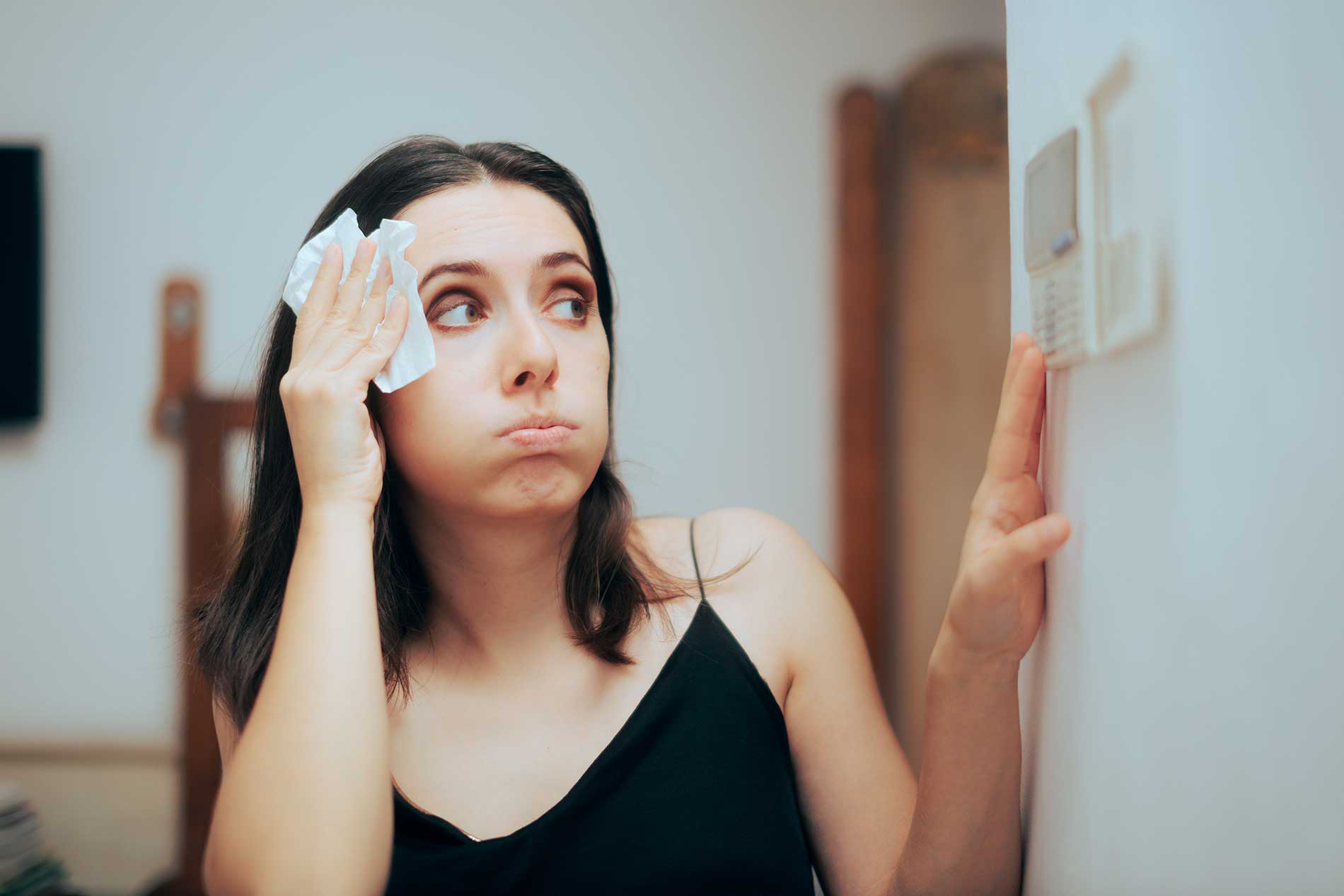 woman-sweating-while-looking-at-a-themostat-inside-the-house woman-sweating-while-looking-at-a-themostat-inside-the-house